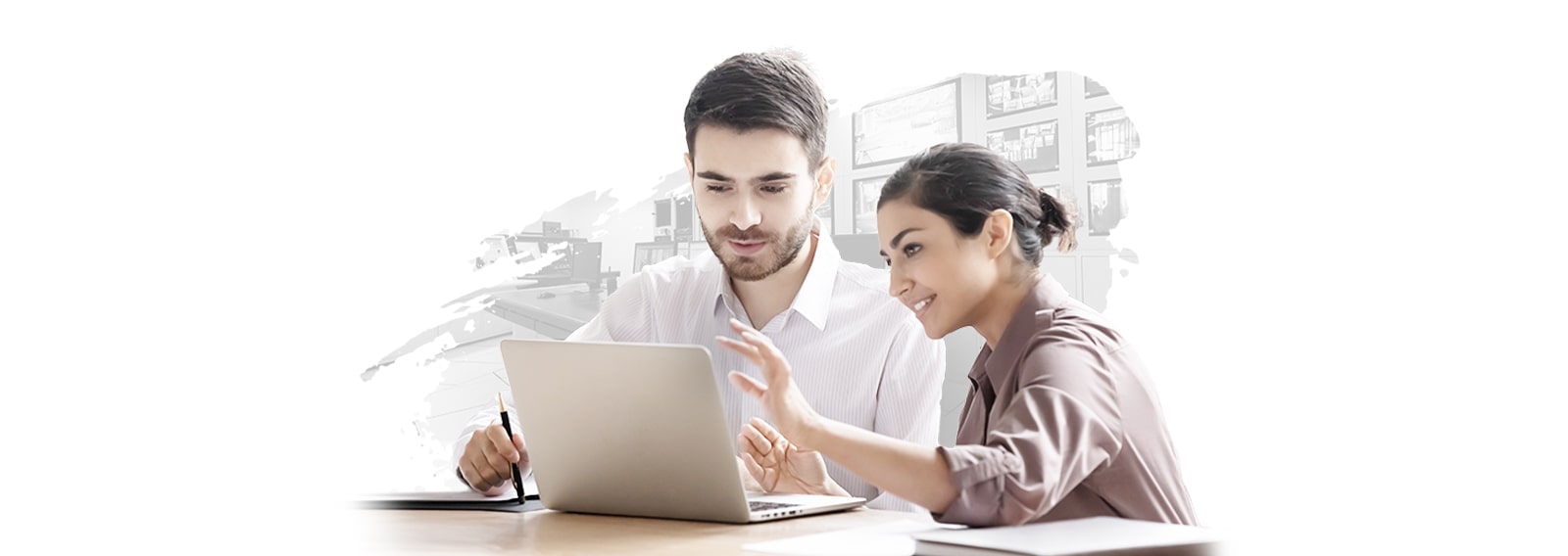 A man and a woman are seated at a desk, collaboratively working while viewing a laptop screen. The background showcases a stylized, abstract design, reflecting a modern, tech-savvy environment.