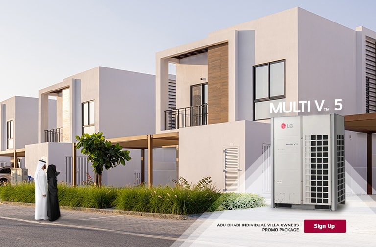 LG Multi V TM 5 HVAC unit prominently displayed in a modern residential setting, flanked by a man and woman in traditional attire, with stylish villas lining the street.