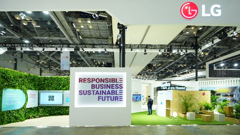 The LG booth is a standout, featuring bold ad text at the center, surrounded by an attractive display of green plants.