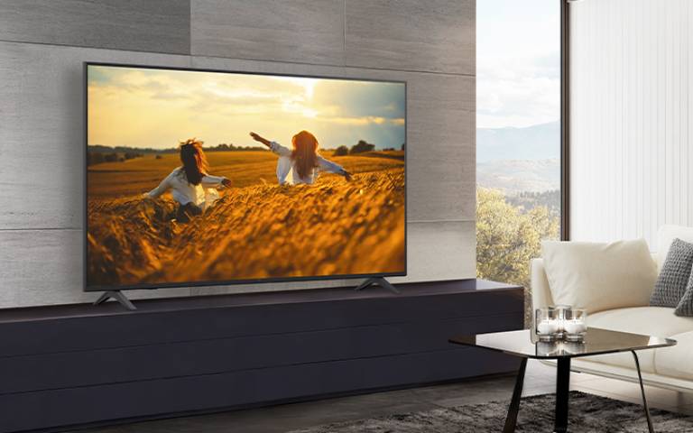 A TV is placed on a stand against the wall in the hotel room, and the screen is bright and clear.