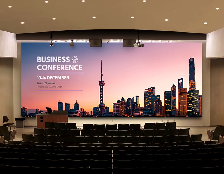 A large LED screen is installed in the auditorium, displaying the conference's agenda.