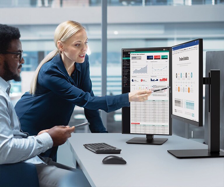 Two male and female employees discuss while looking at the monitor in the office.	