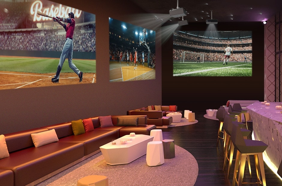 Three projectors are mounted on the ceiling of the sports bar, each playing videos of baseball, basketball, and soccer.	