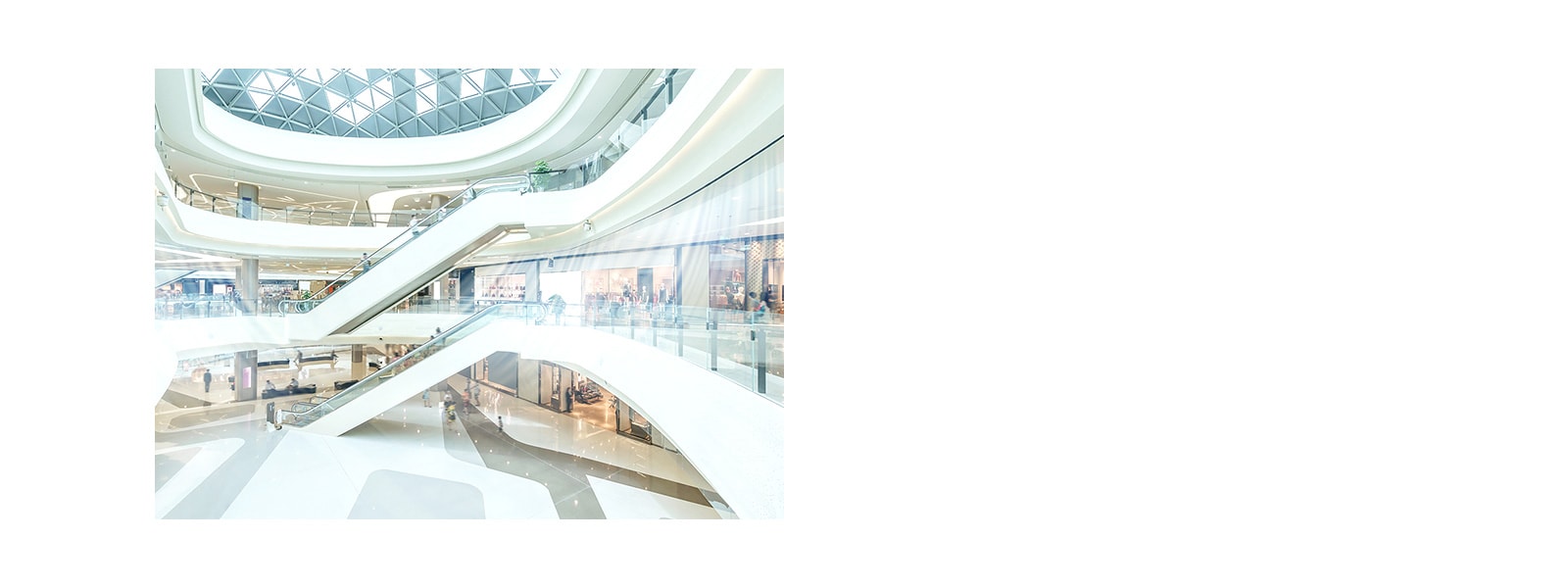 Ceiling concealed ducts supply blue-colored air stream in a large three-storied atrium building with multiple indoor stores and long escalators.