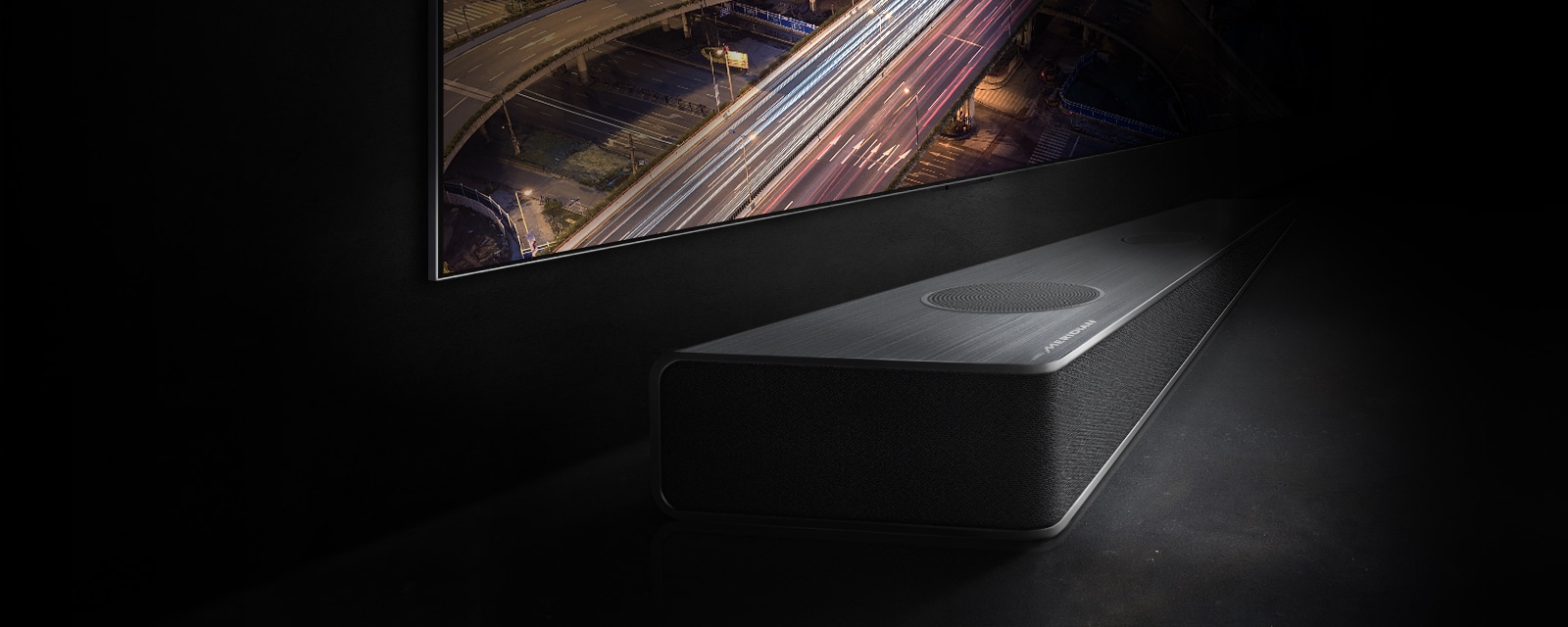 The edge of the soundbar is subtly visible below the TV screen with the night view of the road.