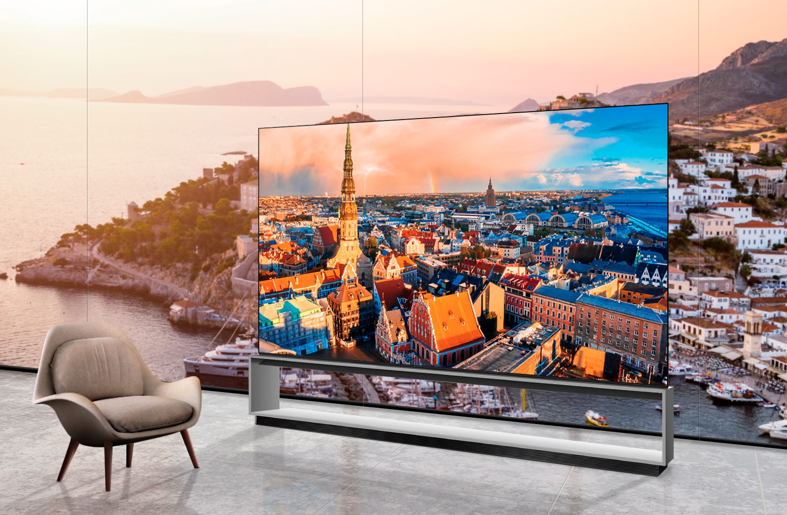 Room overlooking a seaside town. A TV is installed in front of the window showing a view of a city skyline. There is a chair next to the TV.