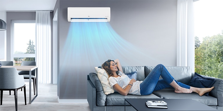 A woman resting on a sofa in the cool breeze of the air conditioner