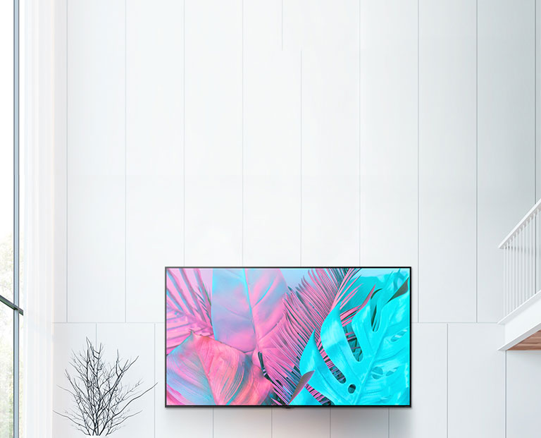 A large flatscreen TV mounted against a white wall. The screen shows large leaves in bright colors.