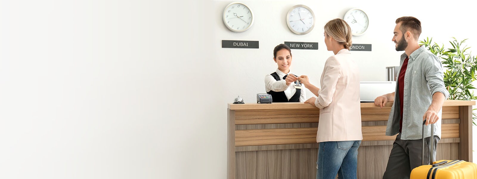 An image of a couple checking in with a receptionist at a hotel lobby.