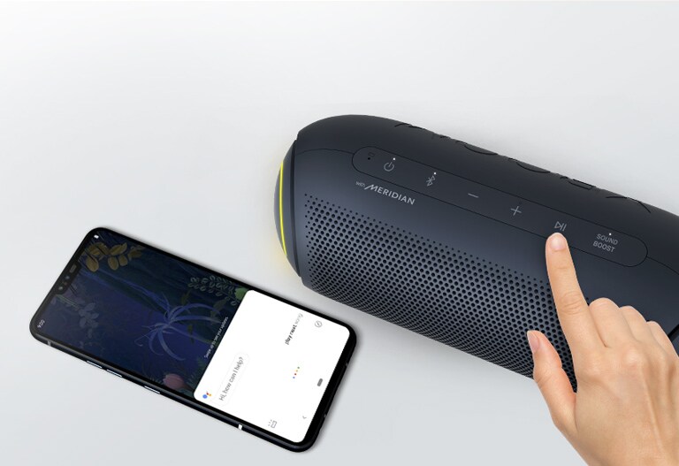 A hand presses a button on LG XBOOM Go. A smartphone is next it. There's a speech bubble. Google's logo is in the top right.