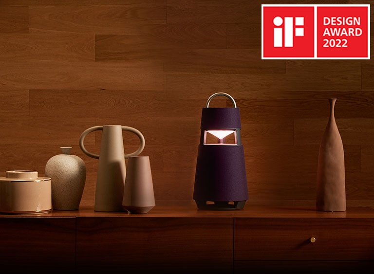 Image of the XBOOM 360 with sculptures on a shelf in a wood-toned interior background. 