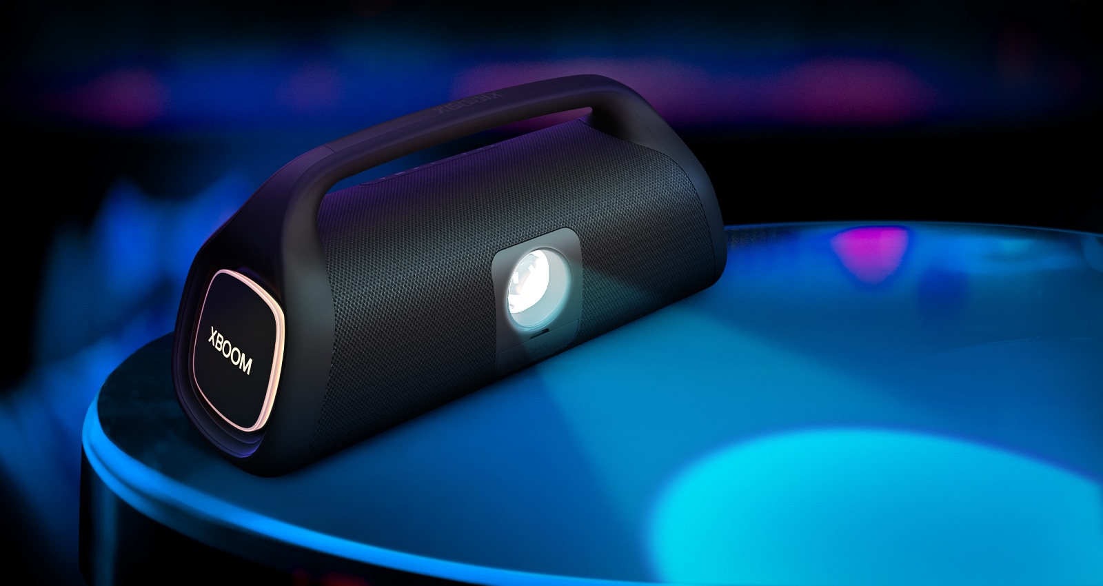 LG XBOOM Go XG9 is placed on the surface, showing its stage lighitng bulb. The bulb casts a blue spotlight, and on the side, an organe lighting is on.