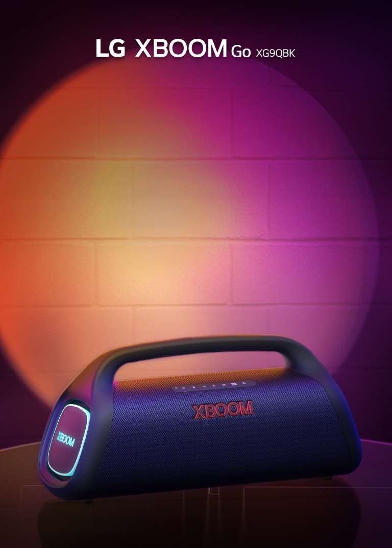 LG XBOOM Go XG9 is placed on the metal table with orange lighting is on. Behind the table, stage lighting is spotlighting the wall.