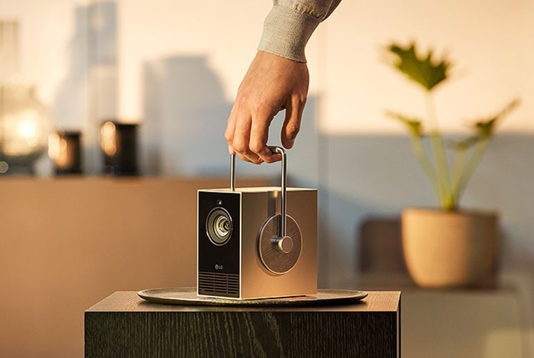 It shows a person effortlessly lifting the Cinebeam Q projector with one hand, highlighting its lightweight design.