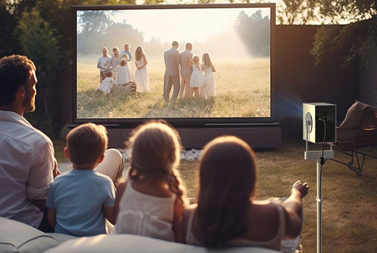 A father and his three children enjoy a video outdoors using a Cinebeam Q with a stand.	