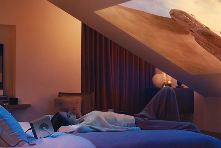 Video of function - A scene where the projector automatically adjusts when a woman places it on the bed.	