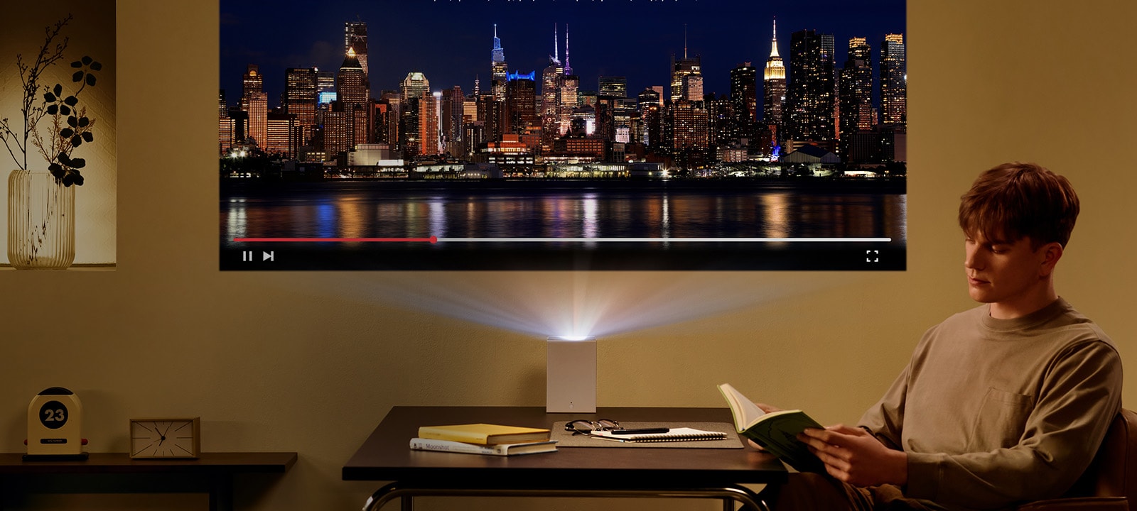 Man reading a book with LG CineBeam projection in the background.	