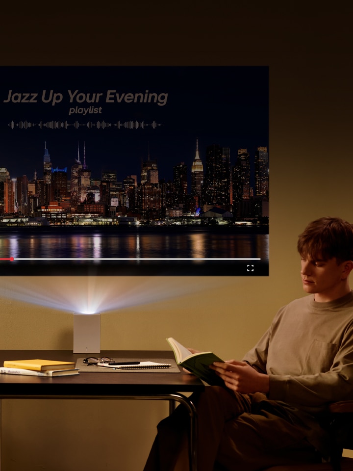 Man reading a book with LG CineBeam projection in the background.	