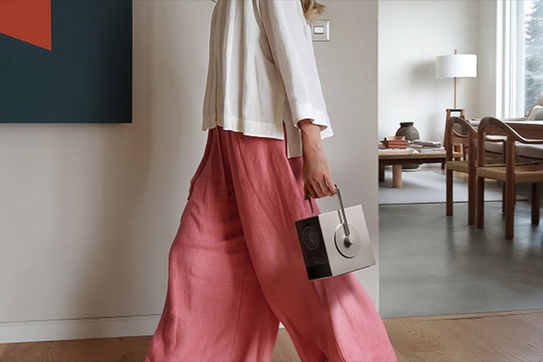 Image of a person carrying the LG CineBeam Q with a handle.