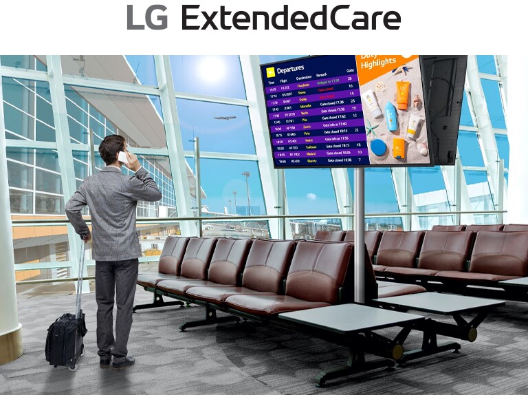 A traveler stands in an airport lounge, checking his phone while looking at a digital departure board displaying flight schedules. The scene highlights the modern, efficient use of signage for real-time updates.
