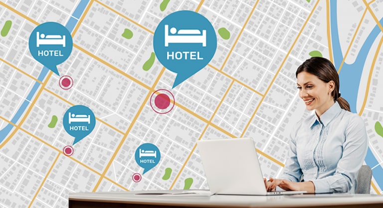 A woman sitting at the desk is using her PC to manage hotel TVs across different locations.