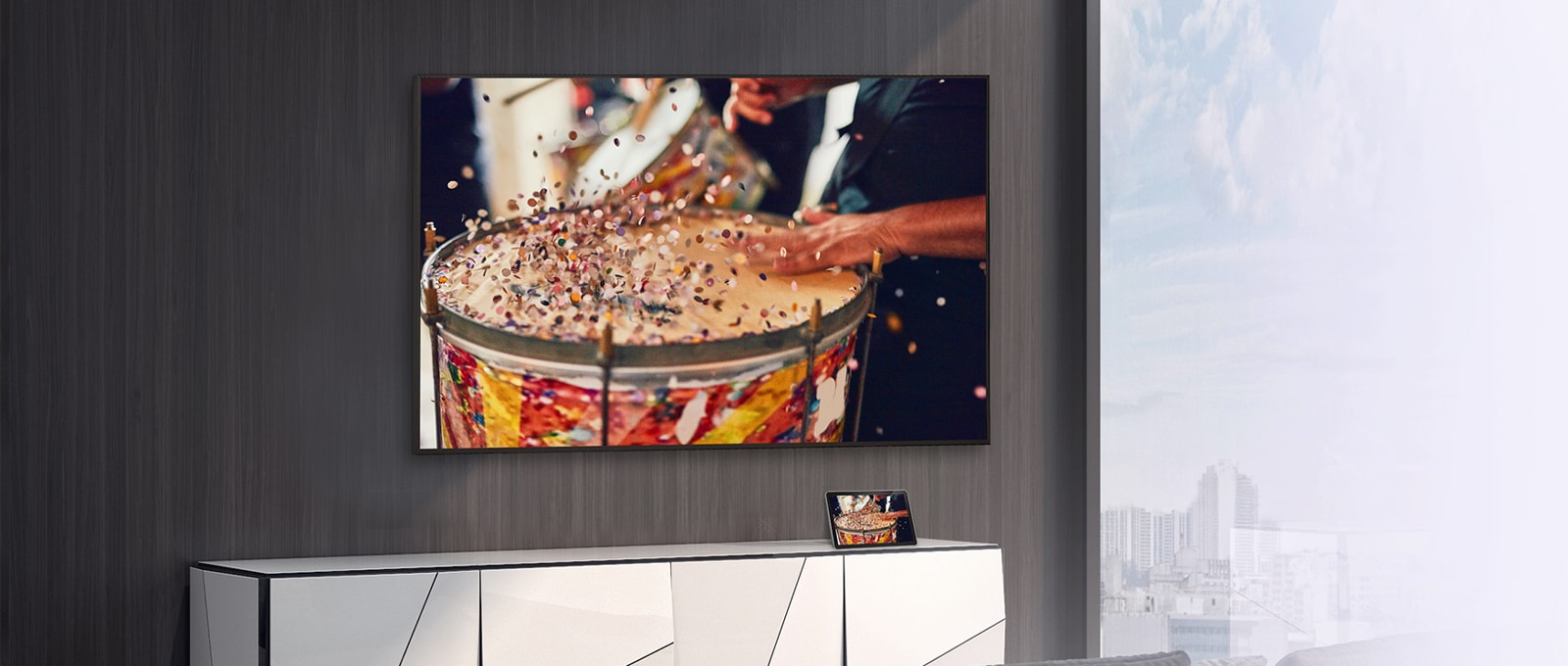 In the room, a wall-mounted TV is set up, with a tablet placed on the shelf. The tablet’s content is mirrored and displayed on the TV.