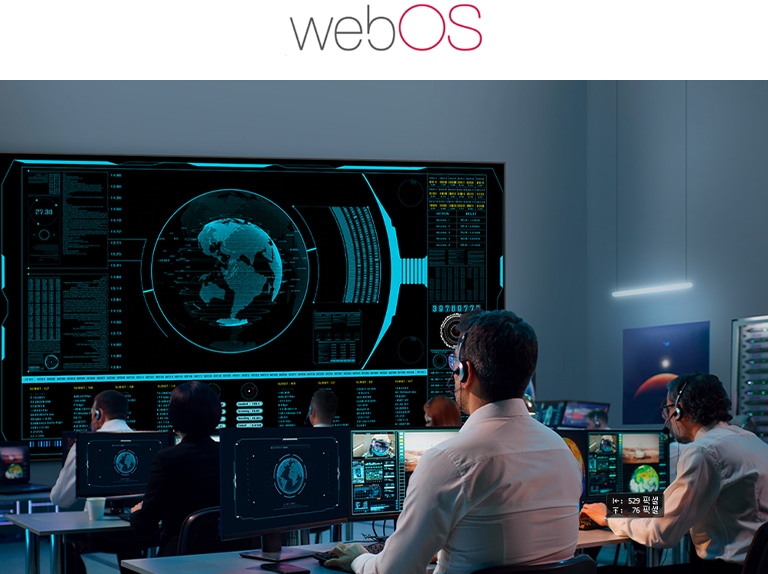 This image shows several people monitoring multiple displays in a control room.