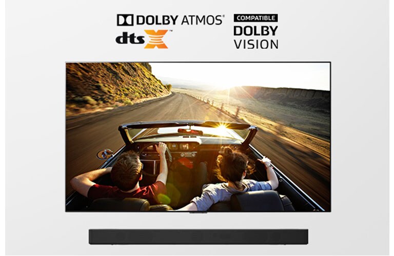TV and Soundbar together in full view. TV shows a couple in an open roof car on the road driving into the sunset. 