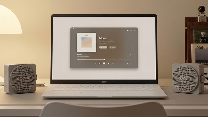 Two LG xboom Mini speakers automatically connected in stereo mode beside a laptop for immersive dual-speaker sound.