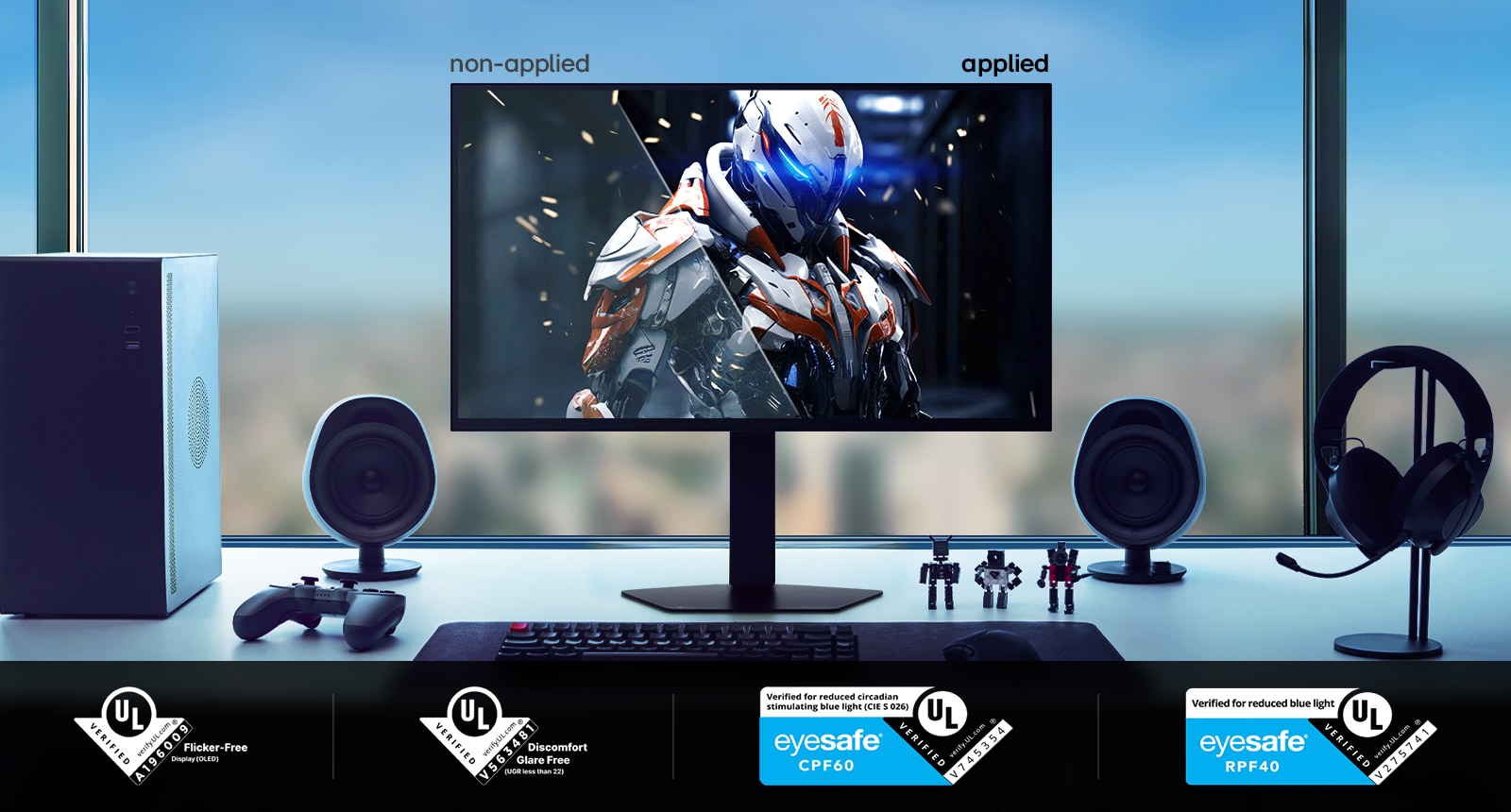LG UltraGear 27GX790B monitor on a desk setup displaying a side-by-side comparison labeled ‘non-applied’ and ‘applied,’ showing different visual states of a sci-fi armored character. The desk includes speakers, a keyboard, figurines, a controller, a PC tower, and headphones. Along the bottom are multiple UL certification badges for flicker-free, discomfort glare-free, and Eyesafe credentials.