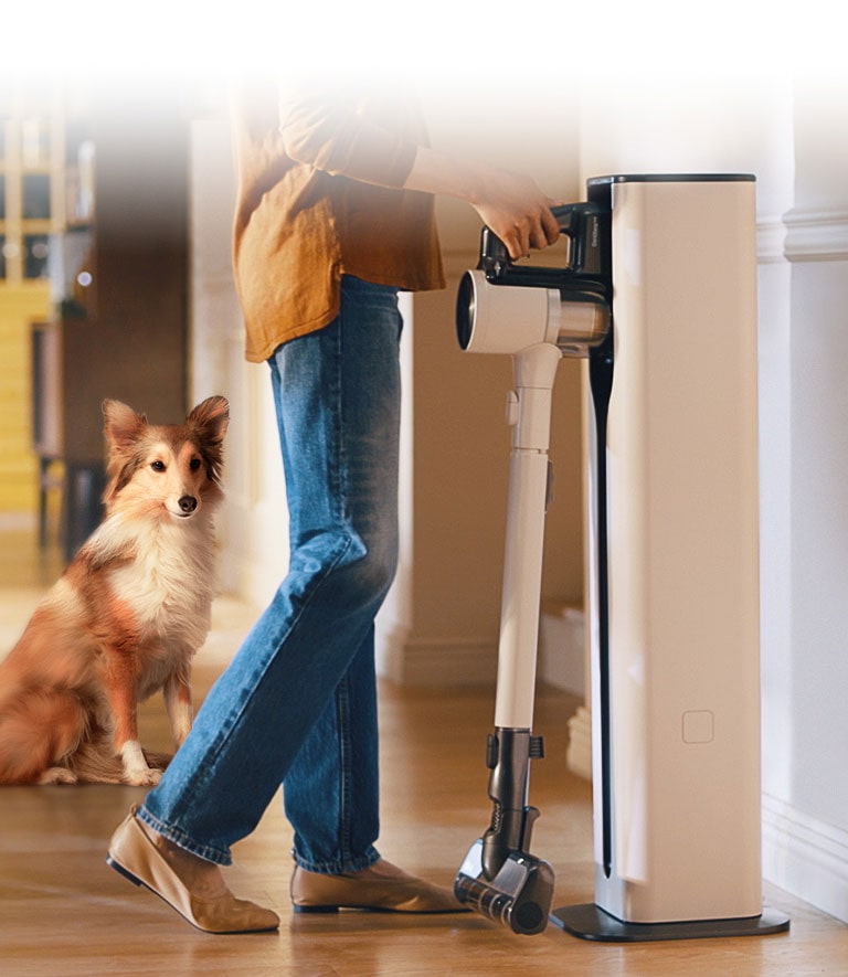 A woman is putting in a Cordzero™ Vacuum cleaner in a docking station.