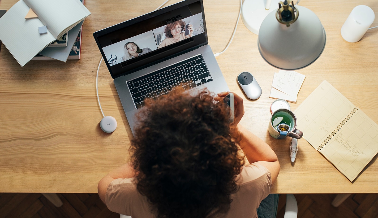 A woman is working on a computer and uses Plug and Wireless to participate in a conference call.