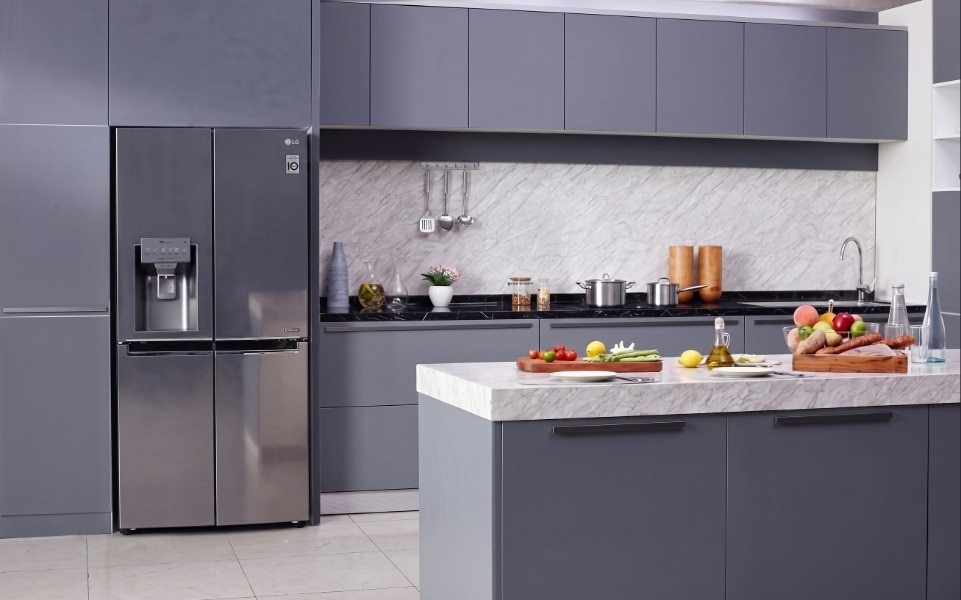 A stainless steel LG multi-door refrigerator standing in a modern gray kitchen with a marble-top island.