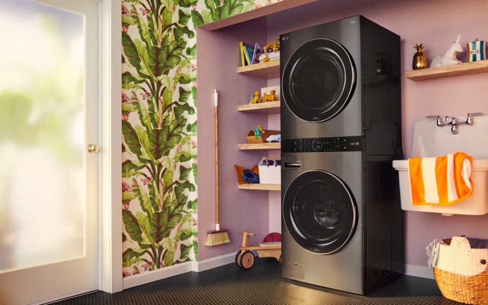 A sleek black LG WashTower in a colorful laundry room with shelves and playful decor.