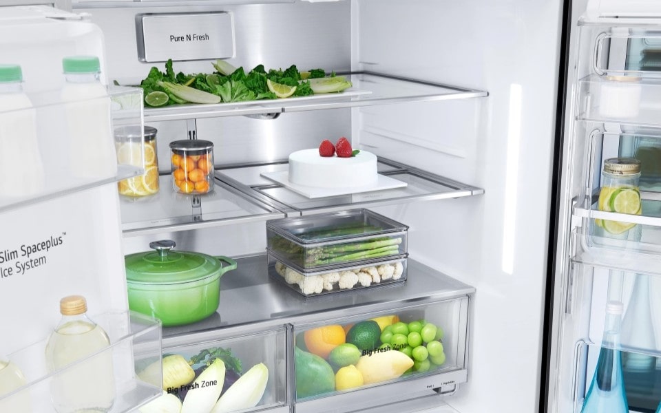 A brightly lit LG refrigerator interior, showcasing various fresh foods, a cake, and organized compartments.