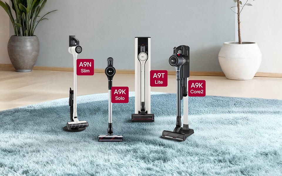 Four LG CordZero A9 cordless stick vacuum cleaner models are arranged on a light blue, plush area rug.