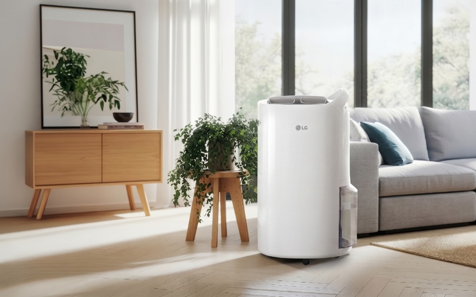 A white LG dehumidifier in a modern, plant-filled living room with light floors.