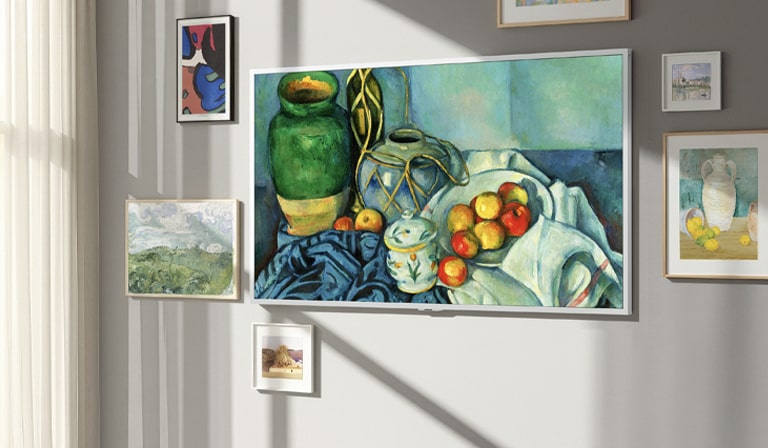 LG Gallery TV AI with frame LX7 ART TV featuring a Gallery-like Screen is wall-mounted with a still life painting on display. It’s positioned near a window with other framed artworks and despite the sunlight, its screen has no visible reflections, making it look like real art.
