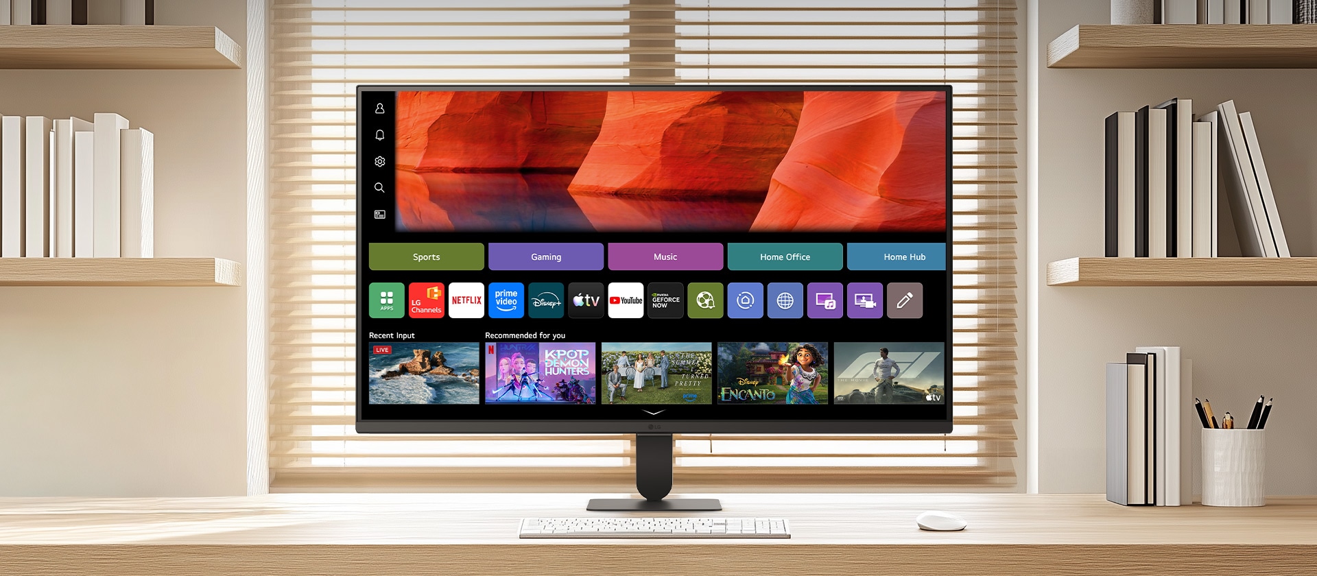 شاشة LG Smart Monitor موضوعة على مكتب خشبي أنيق في مكتب منزلي مشرق، تعرض شاشة webOS الرئيسية مع تطبيقات البث ومربعات المحتوى، إلى جانب لوحة مفاتيح وماوس، ورف كتب وستائر نافذة في الخلفية، مما يسلط الضوء على الاستخدامات الترفيهية والإنتاجية الذكية.
