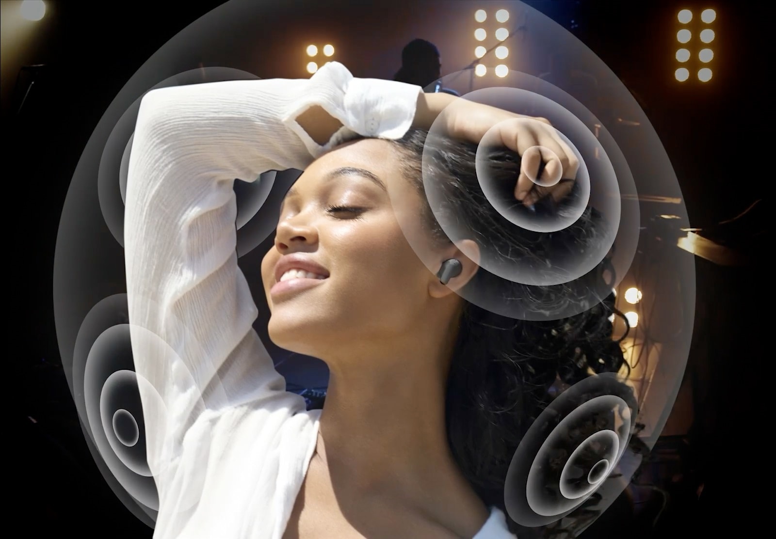 امرأة تستخدم هاتفها وتستمع إلى الموسيقى باستخدام T90. يتغير المشهد من حولها إلى حفل موسيقي مع موجات صوتية تُظهر صوت Dolby Atmos.