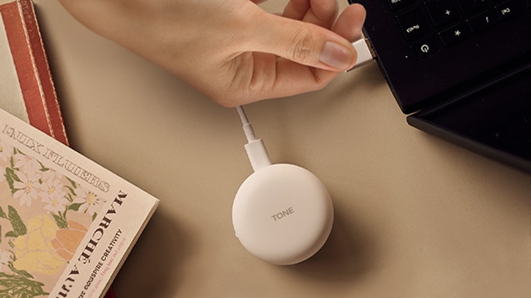 على اليسار، يد توصِّل الحامل بالمنفذ. على اليمين، امرأة تضع سماعات الأذن في أذنها لاستخدام «التوصيل والتشغيل اللاسلكي».