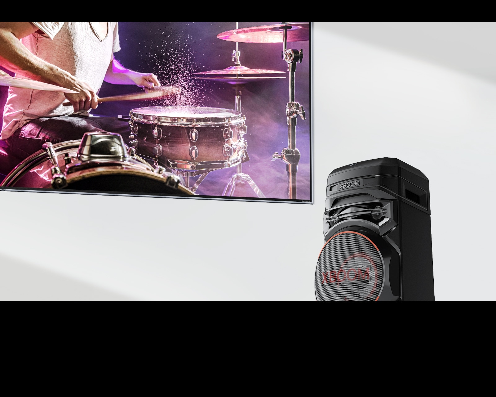 يوجد جهاز التلفزيون على الجدار مع وجود جهاز LG XBOOM على يمينه.