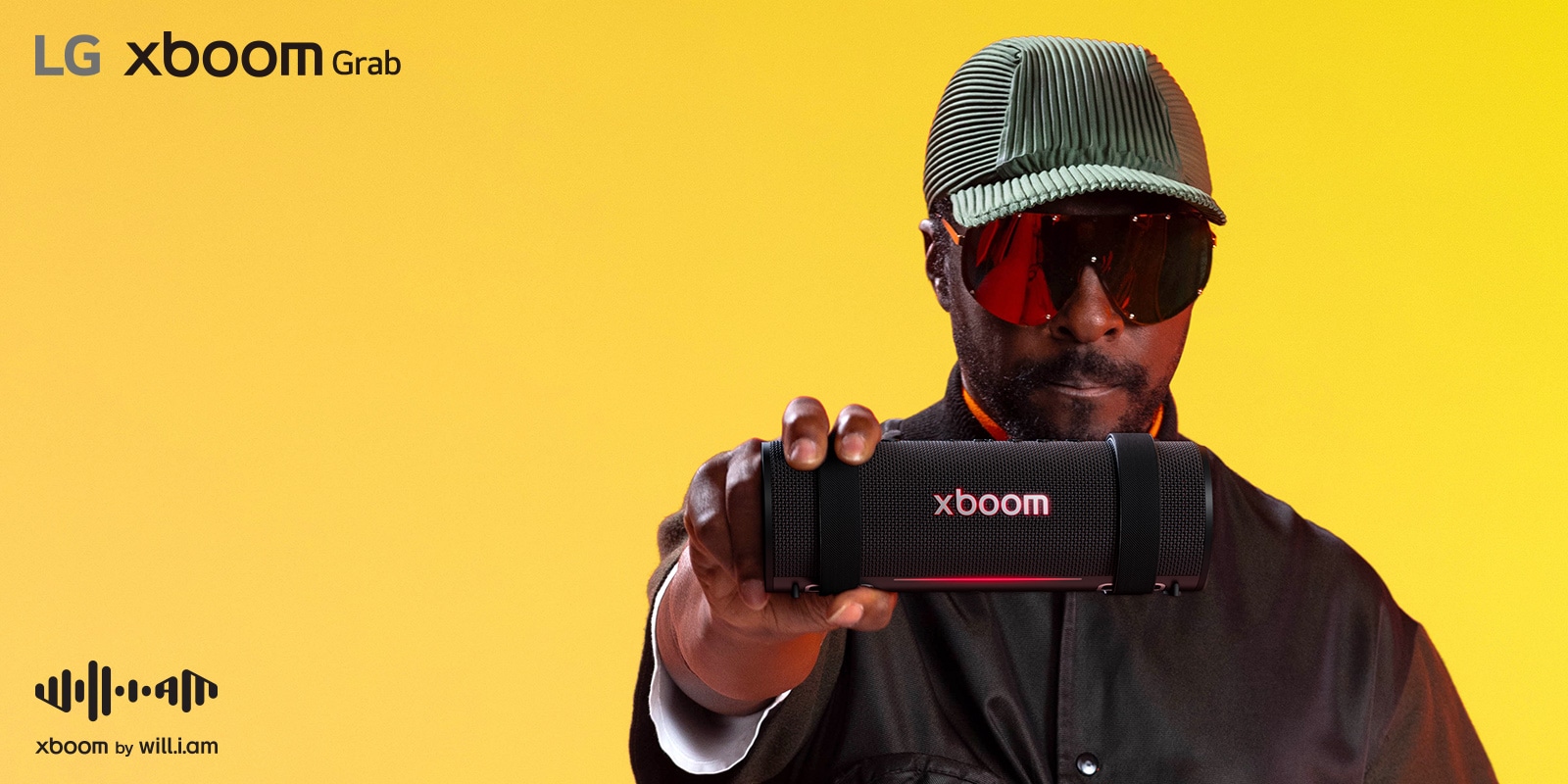 يظهر will.i.am مرتديًا زيًا أسود ونظارات شمسية، وهو يحمل جهاز xboom Grab إلى الأمام.