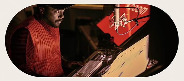 will.i.am في الاستوديو يركّز على شاشة أمامه تقع تحت الميكروفون.