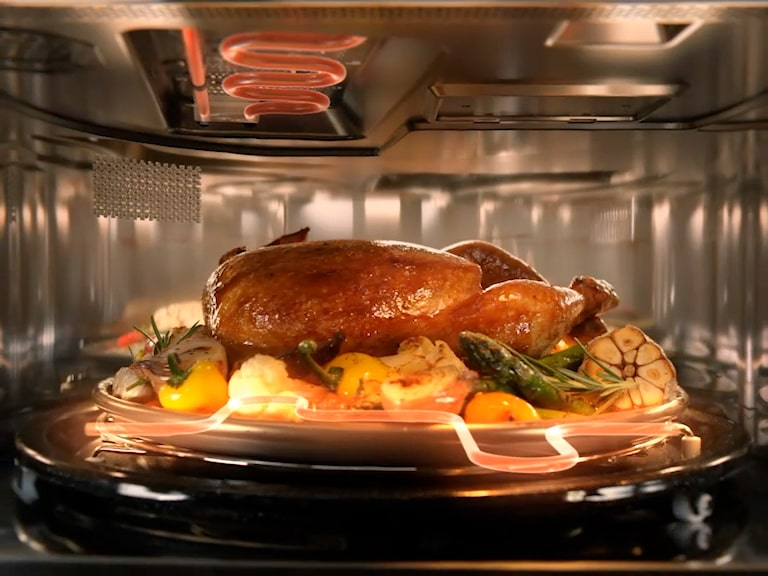 دجاجة كاملة مشوية على صينية دوّارة داخل جهاز LG SolarDOM™، مطهية بشكل متساوٍ مع خضروات تحيط بها.