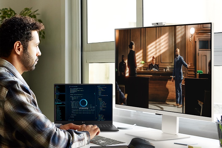 رجل يستمتع ببث المحتوى على شاشة LG MyView Smart Monitor أثناء انتظار اكتمال مهام الكمبيوتر المحمول.	