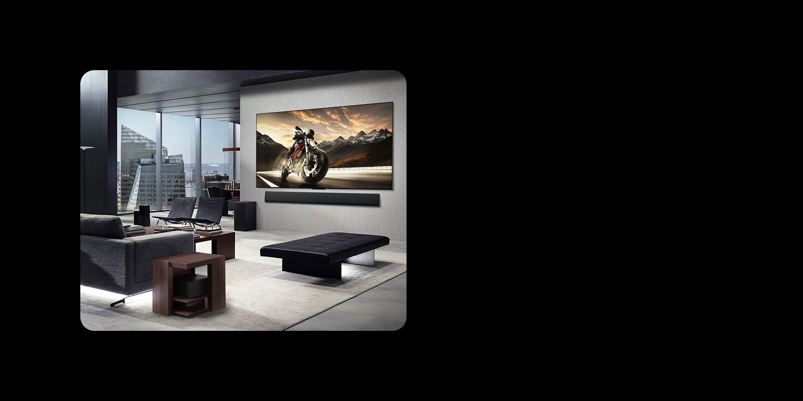 LG OLED M4 ومكبر الصوت LG Soundbar مثبت على جدار غرفة المعيشة في شقة شاهقة الارتفاع. التخطيط خالي من الفوضى. يمكن رؤية صندوق Zero Coonect Box، مخفيًا أسفل طاولة جانبية من خلال أريكة.