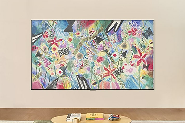 تلفزيون LG ART TV مثبت على الحائط في غرفة مشرقة، ويعرض عملا فنيا ملونا من الزهور والفواكه في وضع المعرض (Gallery Mode)، بينما يضبط التحكم في السطوع الشاشة لتوفير مشاهدة مثالية في أي إضاءة.