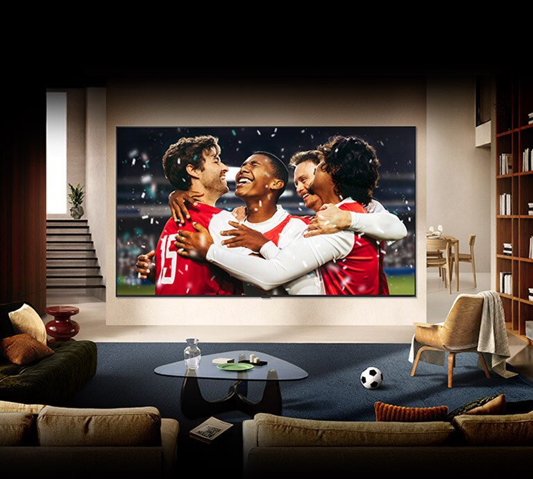يُعرض تلفزيون LG TV مثبتًا على الحائط في غرفة معيشة مشرقة، حيث يُظهر احتفالًا رياضيًا في الاستاد بألوان نابضة بالحياة وجودة صورة مصقولة على شاشة عريضة.