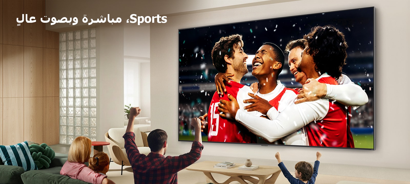 يُعرض تلفزيون LG Ultra Big TV مثبتًا على الحائط في غرفة معيشة مشرقة، حيث يُظهر احتفالًا رياضيًا في الاستاد بألوان نابضة بالحياة وجودة صورة مصقولة على شاشة عريضة، بينما تشجّع عائلة جالسة على الأرائك معًا.
